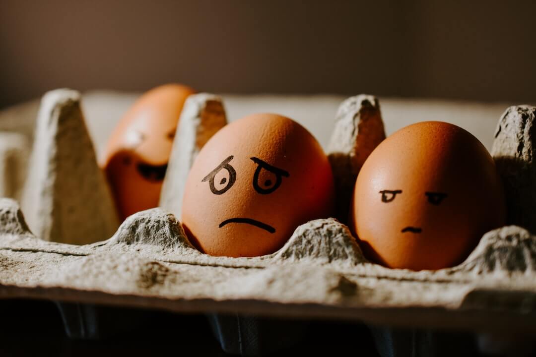 Drei Eier in einem Eierkarton mit aufgemalten Gesichtern.